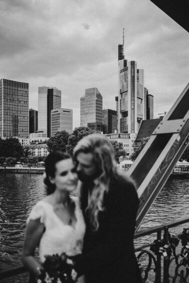 A couple on a bridge with a city skyline in the background. 3