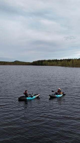 Two kayakers on a calm lake with a forested shoreline. 5