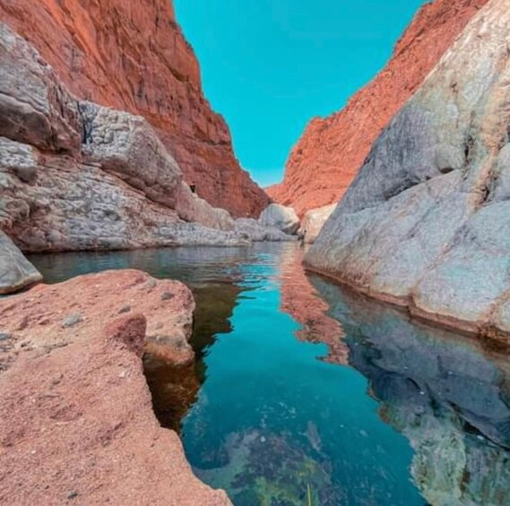 A canyon with a clear blue river reflecting the red rock walls. 3