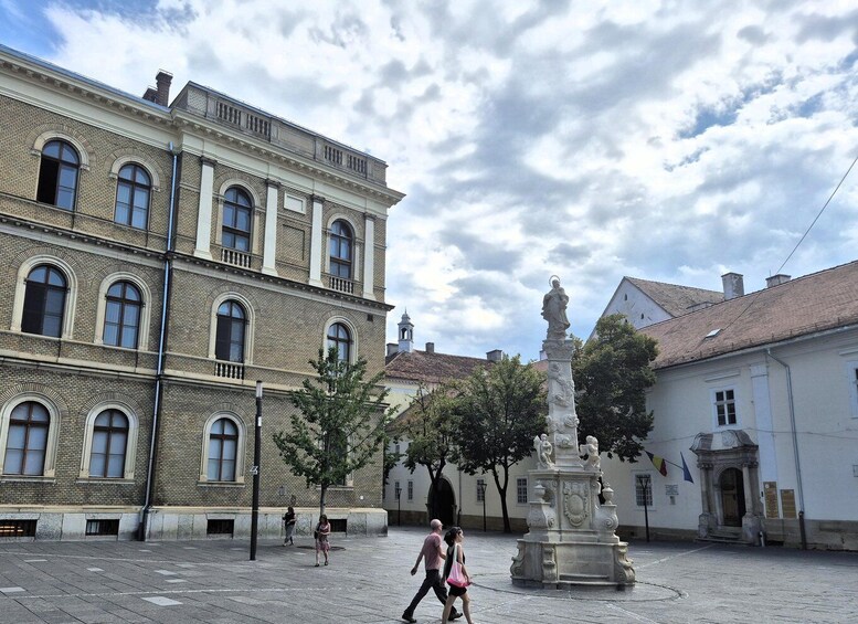 A historic square with a fountain, a statue, and traditional buildings. 2