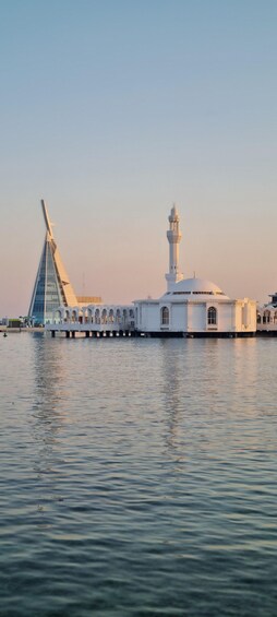 A mosque with a minaret and a modern building across the water. 1