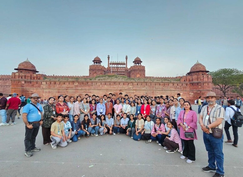 A group of people posing in front of a large historical fort with multiple domes and towers. 4