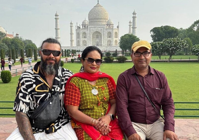 Three people sitting on a bench with the Taj Mahal in the background. 5