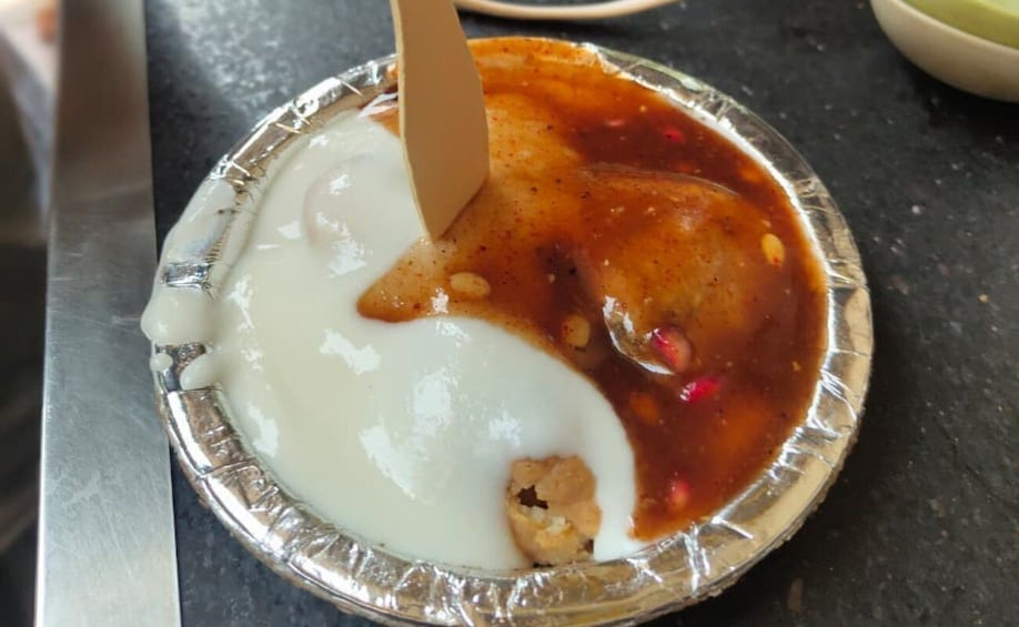 A foil container with a white creamy substance and a reddish sauce, possibly containing food. 5
