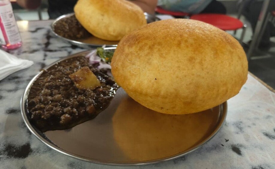 A plate with a breaded item and a deep-fried bun, possibly a type of stuffed bread or pastry. 5