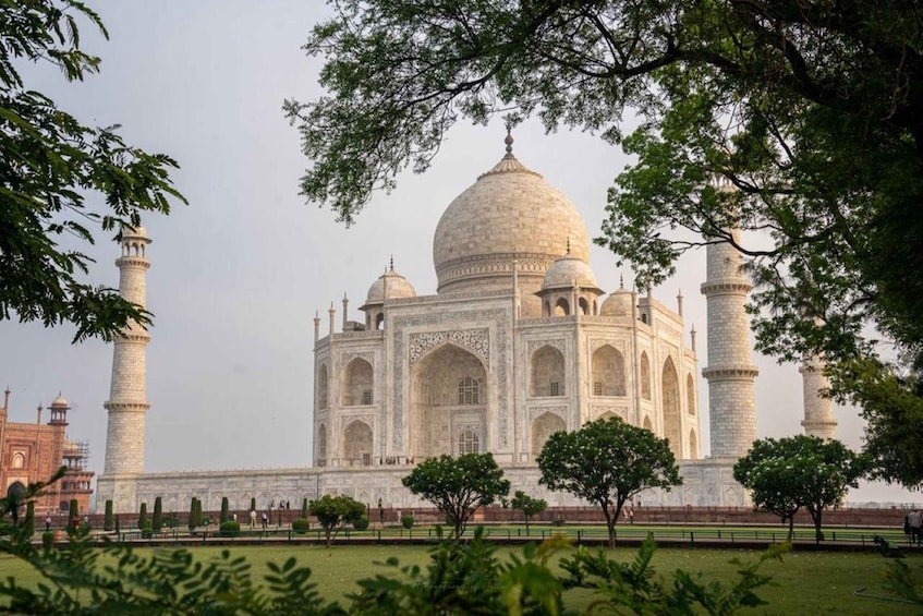 The Taj Mahal with four minarets and a large dome, surrounded by trees and a well-maintained garden. 3