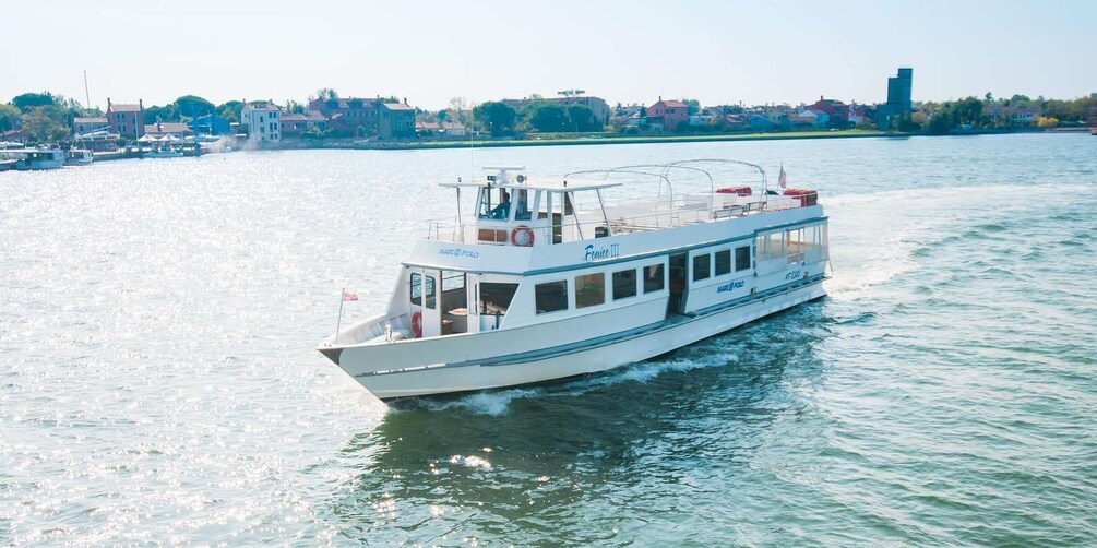 A white boat named 'Venice III' on a river with a cityscape in the background. 3