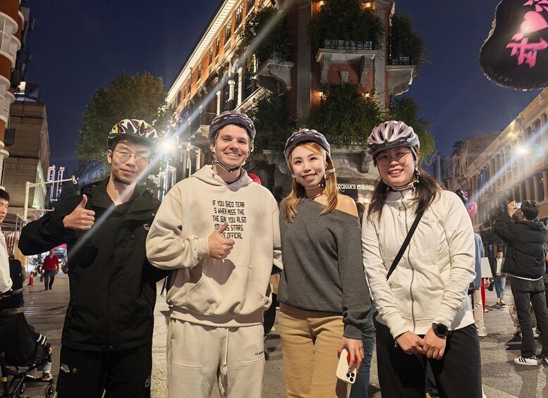 Four people standing on a street at night, wearing casual clothing and helmets. 3
