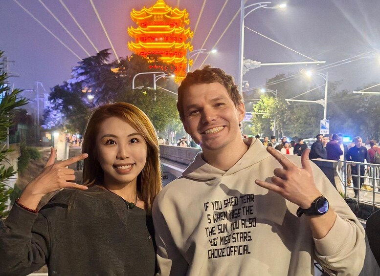 Two people posing with a pagoda in the background. 1