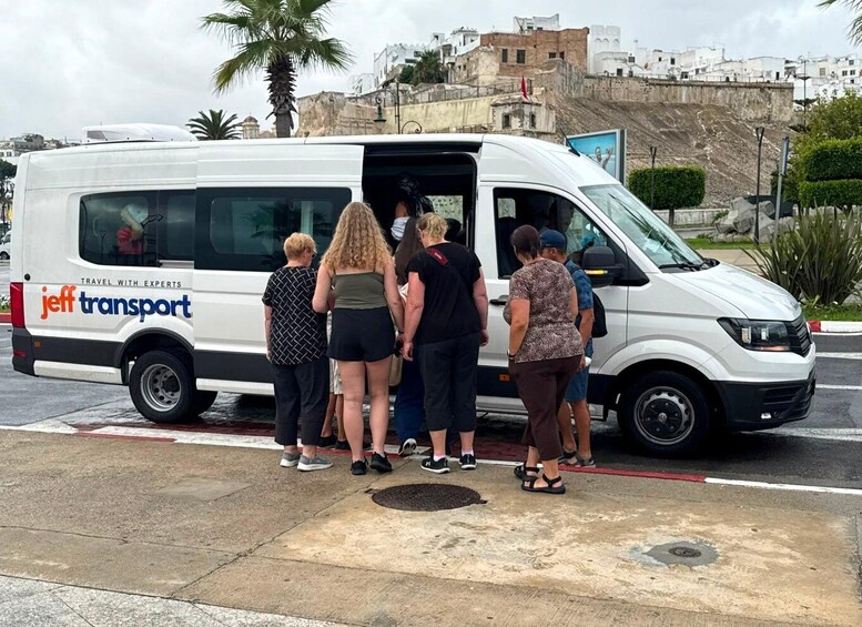 A white van with 'jeff transport' branding parked on a street with a group of people standing beside it. 2
