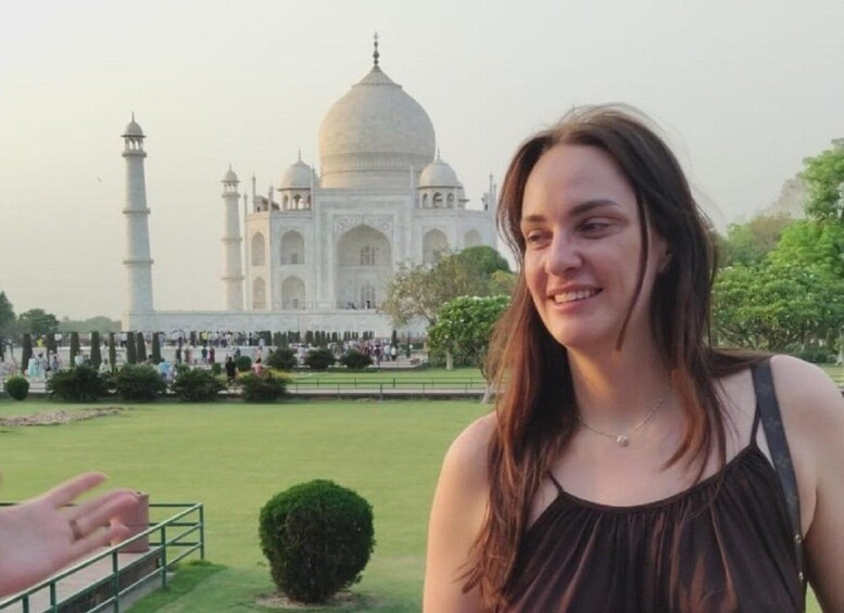 A person standing in front of the Taj Mahal with a clear view of the iconic white marble mausoleum and its four minarets. 5