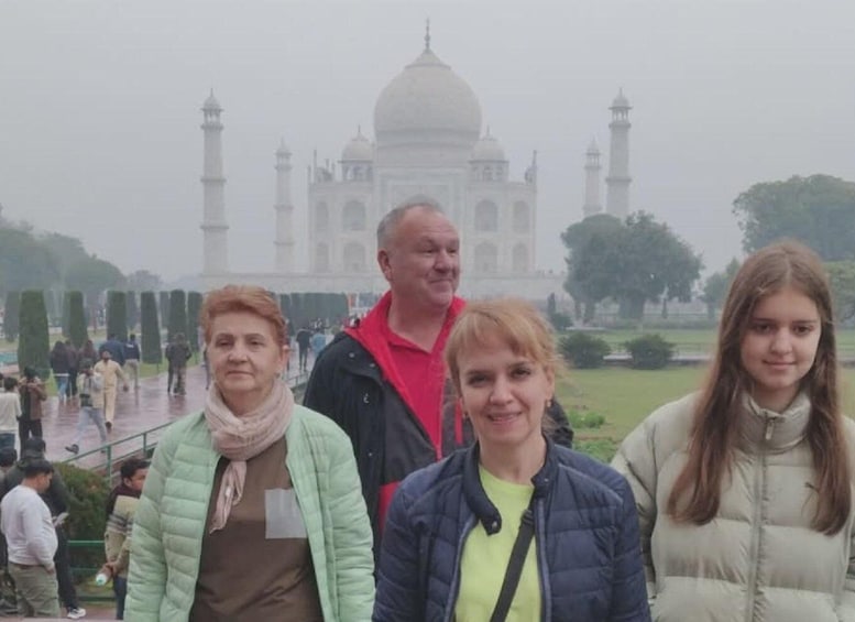 A group of people standing in front of the Taj Mahal with a cloudy sky. 1