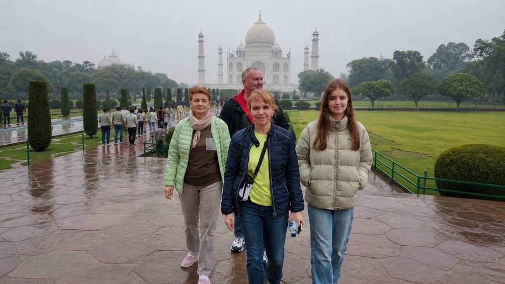 A group of people walking in front of the Taj Mahal on a rainy day. 4
