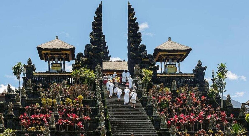 A temple with a staircase, statues, and tropical flowers. 2