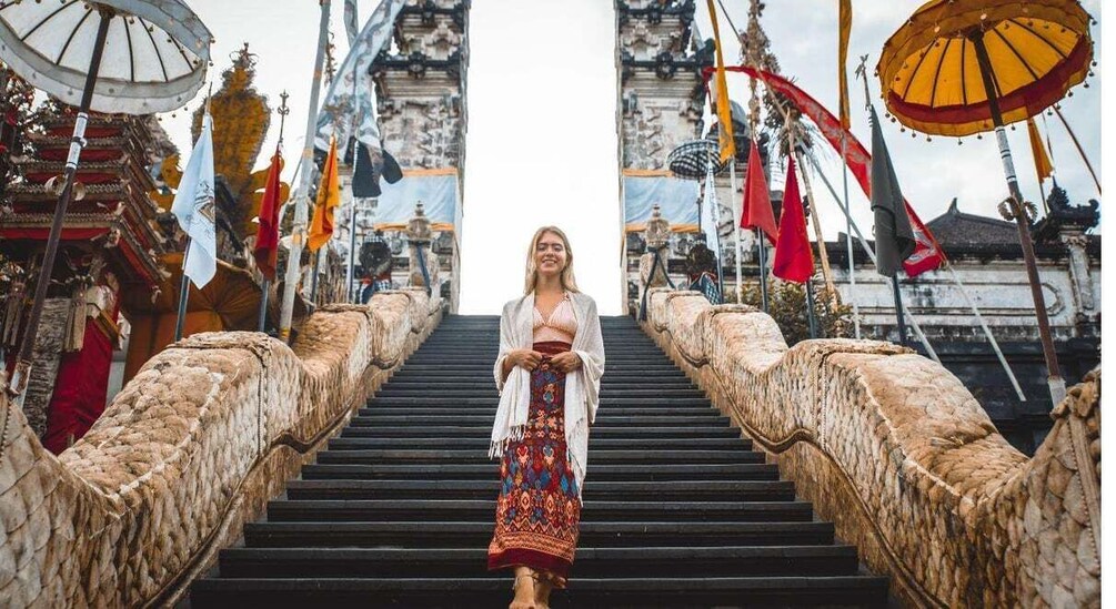 A woman descending a stone staircase flanked by traditional umbrellas and flags. 4