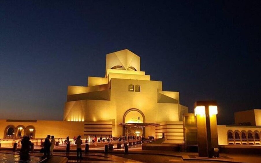 A modern building with a unique geometric design, illuminated at night. 5