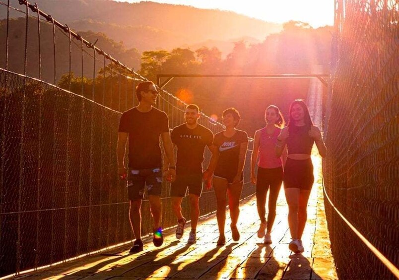 A group of people jogging on a suspension bridge with a sunset in the background. 4