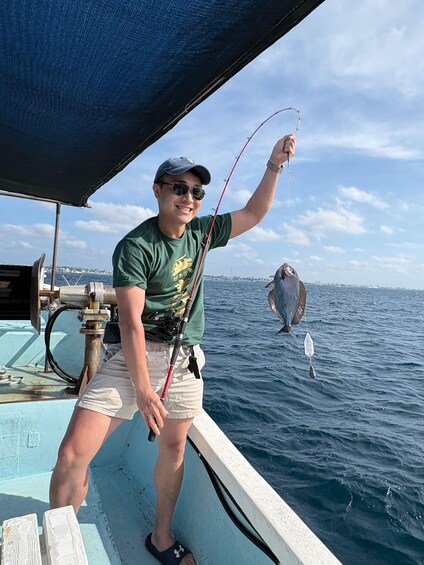A person on a boat holding a fish. 5