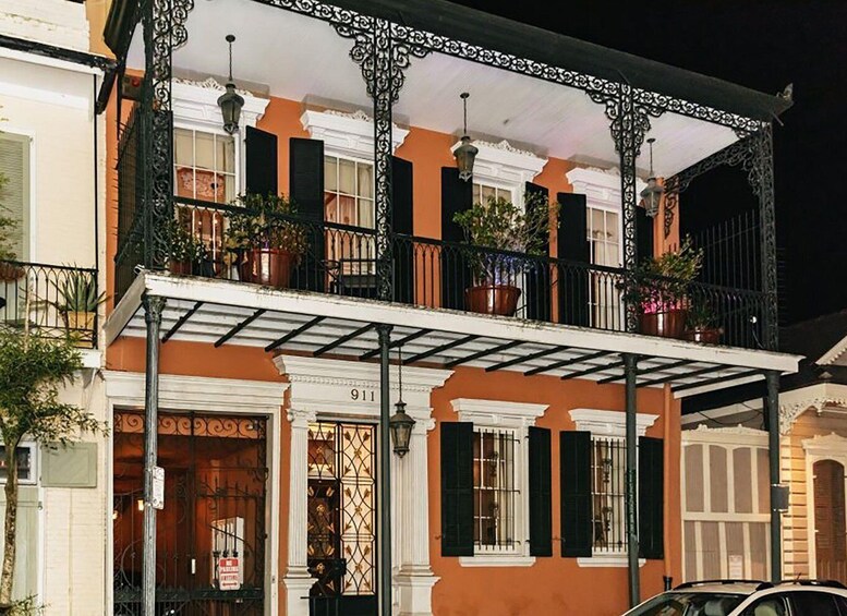 A building with a balcony, potted plants, and a sign with the number 911. 2