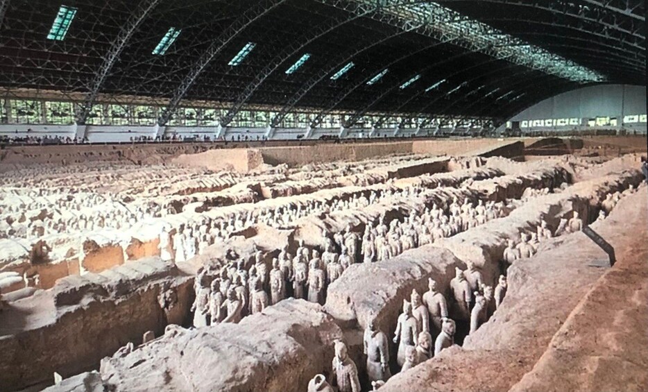 An ancient terracotta army excavation site with rows of statues. 4