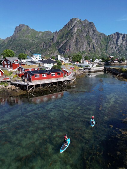 A coastal town with clear waters, a pier, and mountains in the background. 3