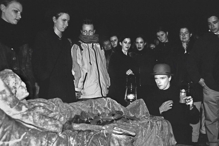 A group of people gathered around a person lying on the ground, some holding lanterns. 4