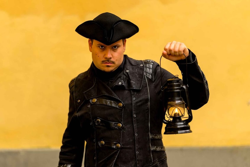 A person in a black jacket and hat holding a lantern. 1
