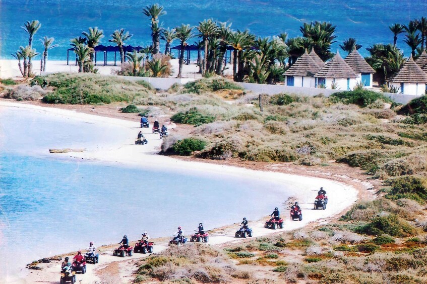A beach with people riding quad bikes along the shore. 5