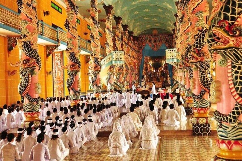 A temple interior with ornate dragon decorations and people in white robes. 5