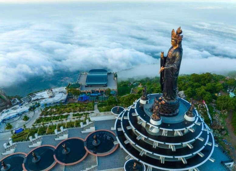 A large statue on a circular platform surrounded by fountains, with a stadium and greenery in the background. 4