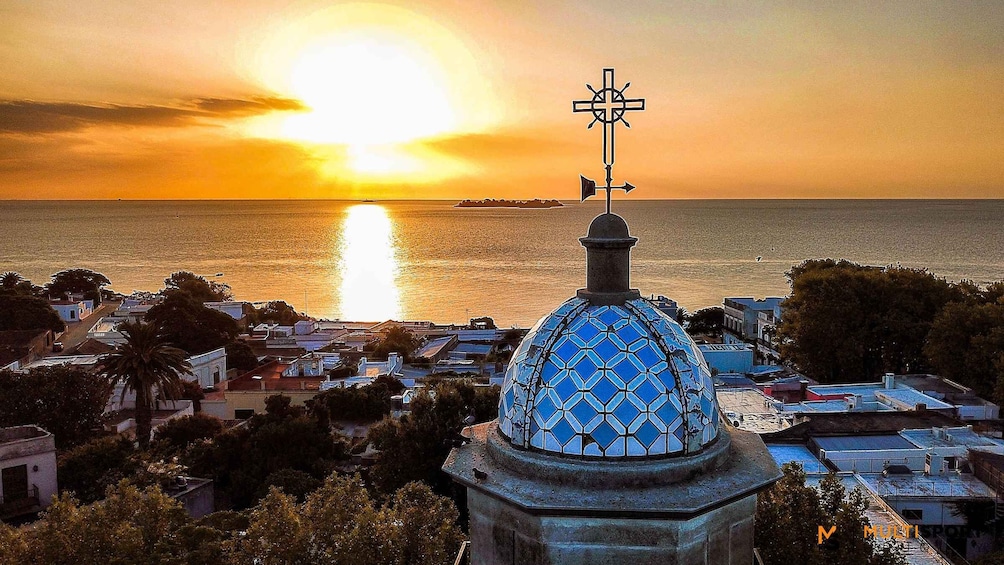 A coastal cityscape with a prominent blue-domed building and a cross atop a tower. 5