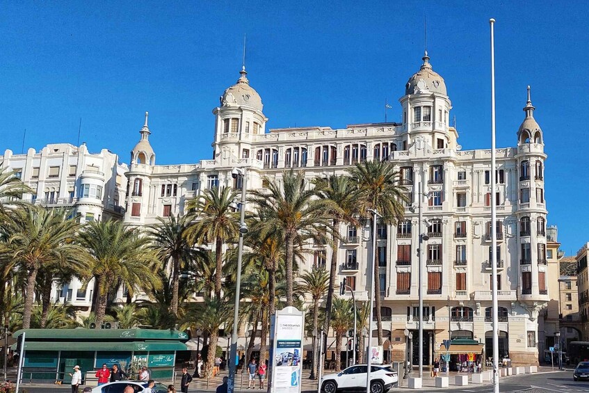A large, ornate building with domes and columns, surrounded by palm trees. 1