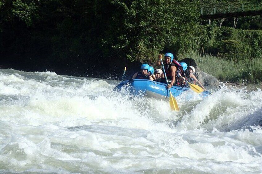 A group of people in a blue raft navigating a river with white water rapids. 5