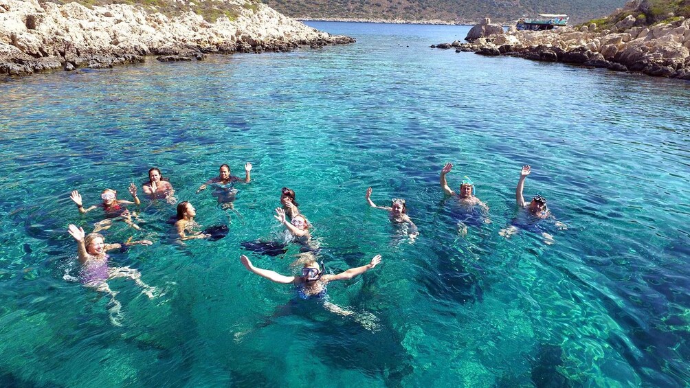 A group of people swimming in clear blue water surrounded by rocky cliffs. 2