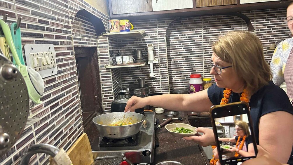A person cooking in a kitchen with a brick-patterned backsplash and various cooking utensils. 5