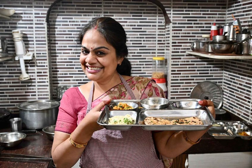 A person holding a stainless steel tray with food items. 1