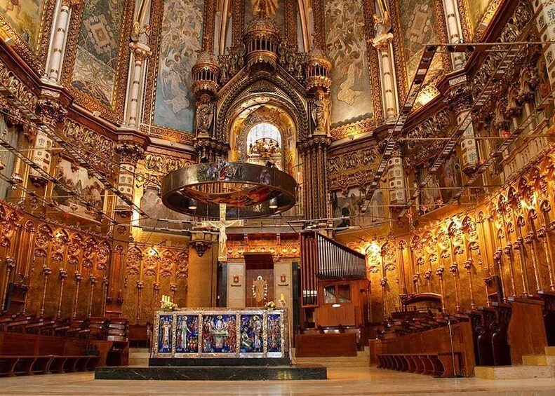 An ornate church interior with intricate woodwork, a central altar, and a large chandelier. 5