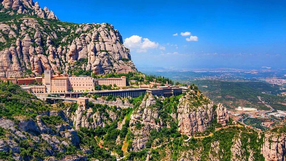 A mountainous landscape with a monastery and buildings on a cliff. 1