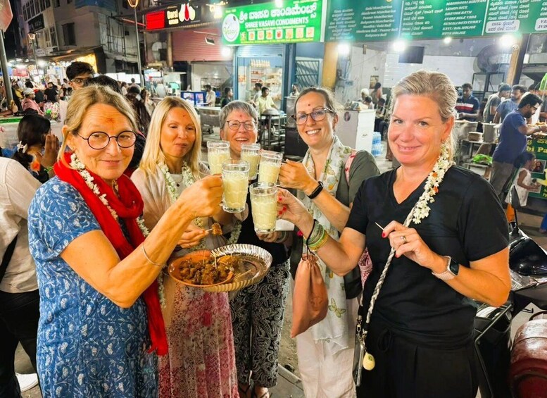 A group of people toasting with drinks in a busy street market. 2