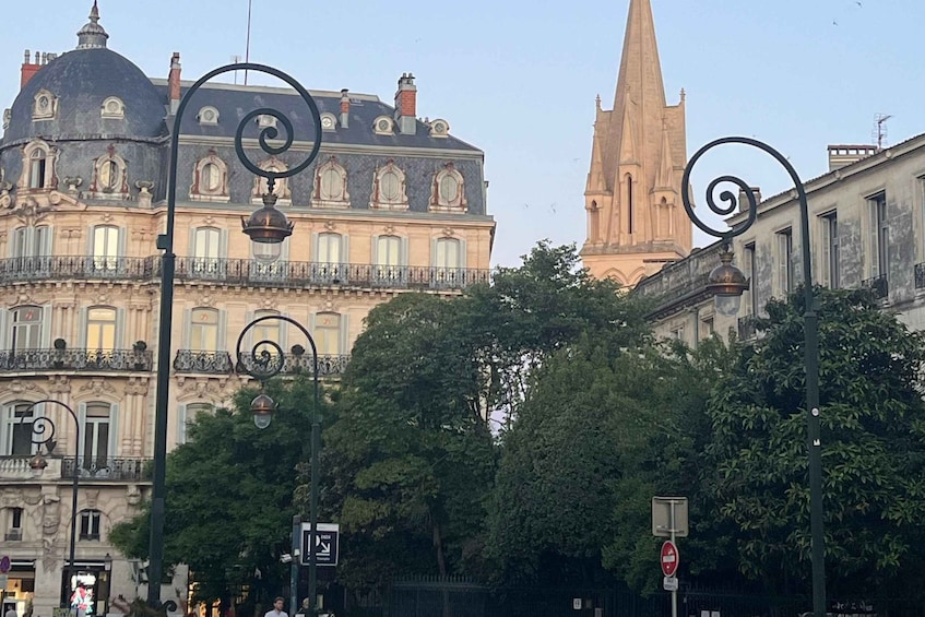 A historic building with ornate balconies and a church spire in the background. 1