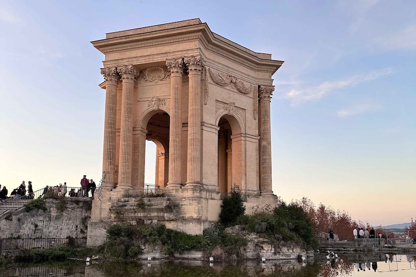 A large classical monument with columns and arches, surrounded by a small body of water and steps leading up to it. 4