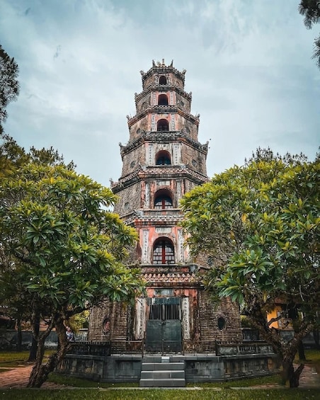 A multi-tiered pagoda with intricate carvings and a traditional roof, surrounded by lush greenery. 5
