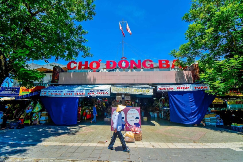 A market entrance with a sign reading "CHO DONG BANG" and various stalls. 3