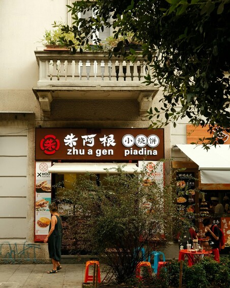 A restaurant with a sign in Chinese characters and a menu board. 1