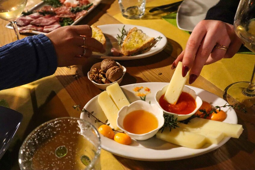 A dining table with various food items including cheese, nuts, and a glass of wine. 2