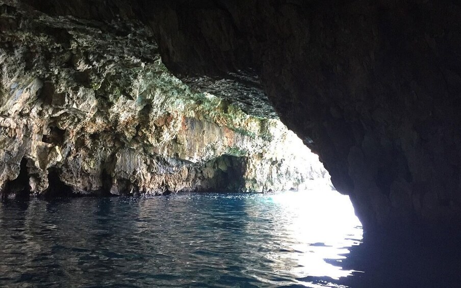 A cave entrance with clear water and sunlight filtering through. 3