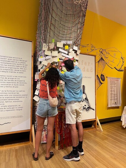 Two people interacting with a wall covered in notes and drawings. 3