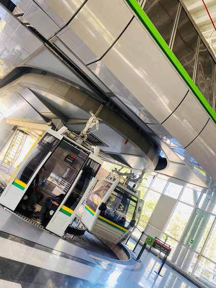 A modern train station with a curved platform, a ticket machine, and a green safety line. 4