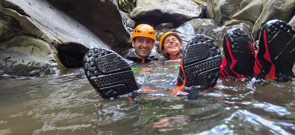 Two people in a rocky stream wearing helmets and waders. 3