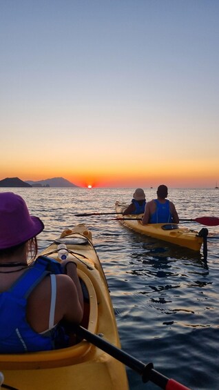 Two people kayaking on a calm body of water during sunset. 3